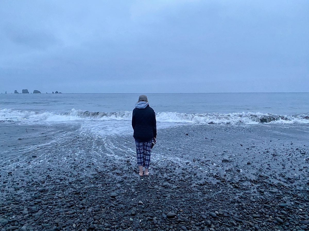 teenage girl staring at the ocean at First Beach in La Push with sea stacks in the distance