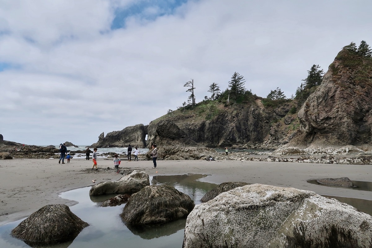kids playing on Second Beach in Olympic National Park with natural arch in the background