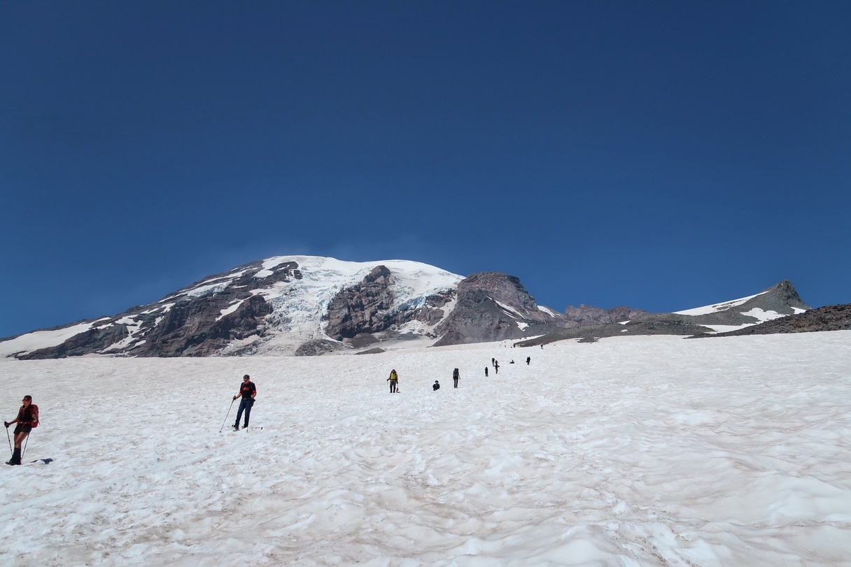 A line of hikers on snow-covered mountain terrain on the hike to Camp Muir.