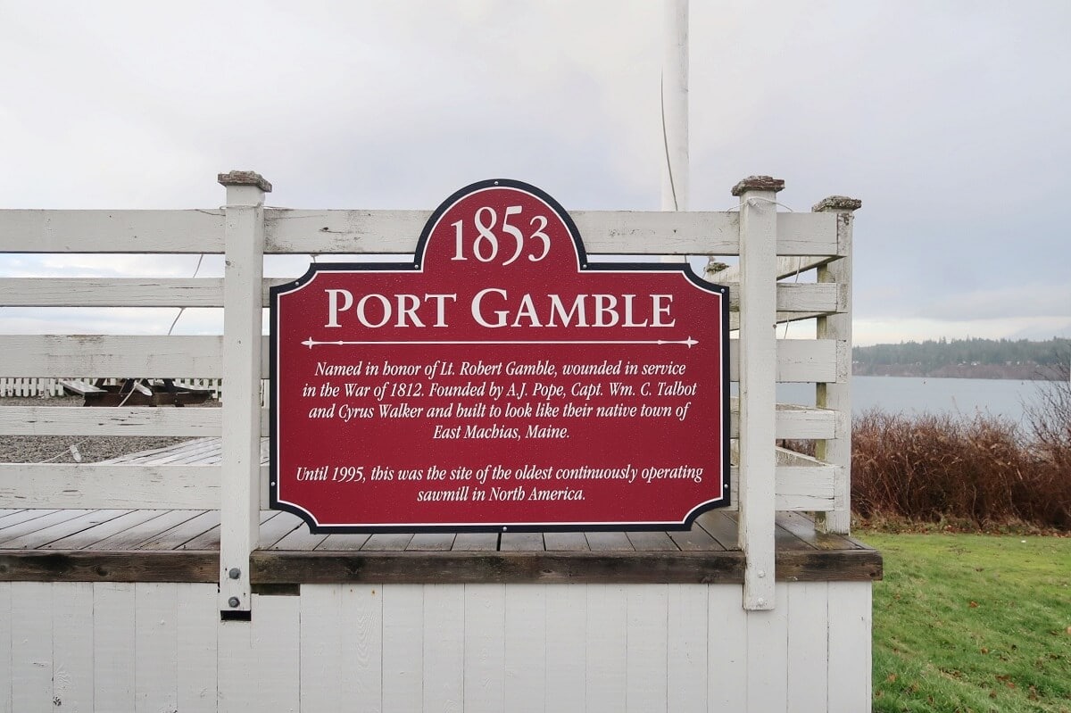 Historical sign of Port Gamble, detailing its founding in 1853, against a waterfront backdrop