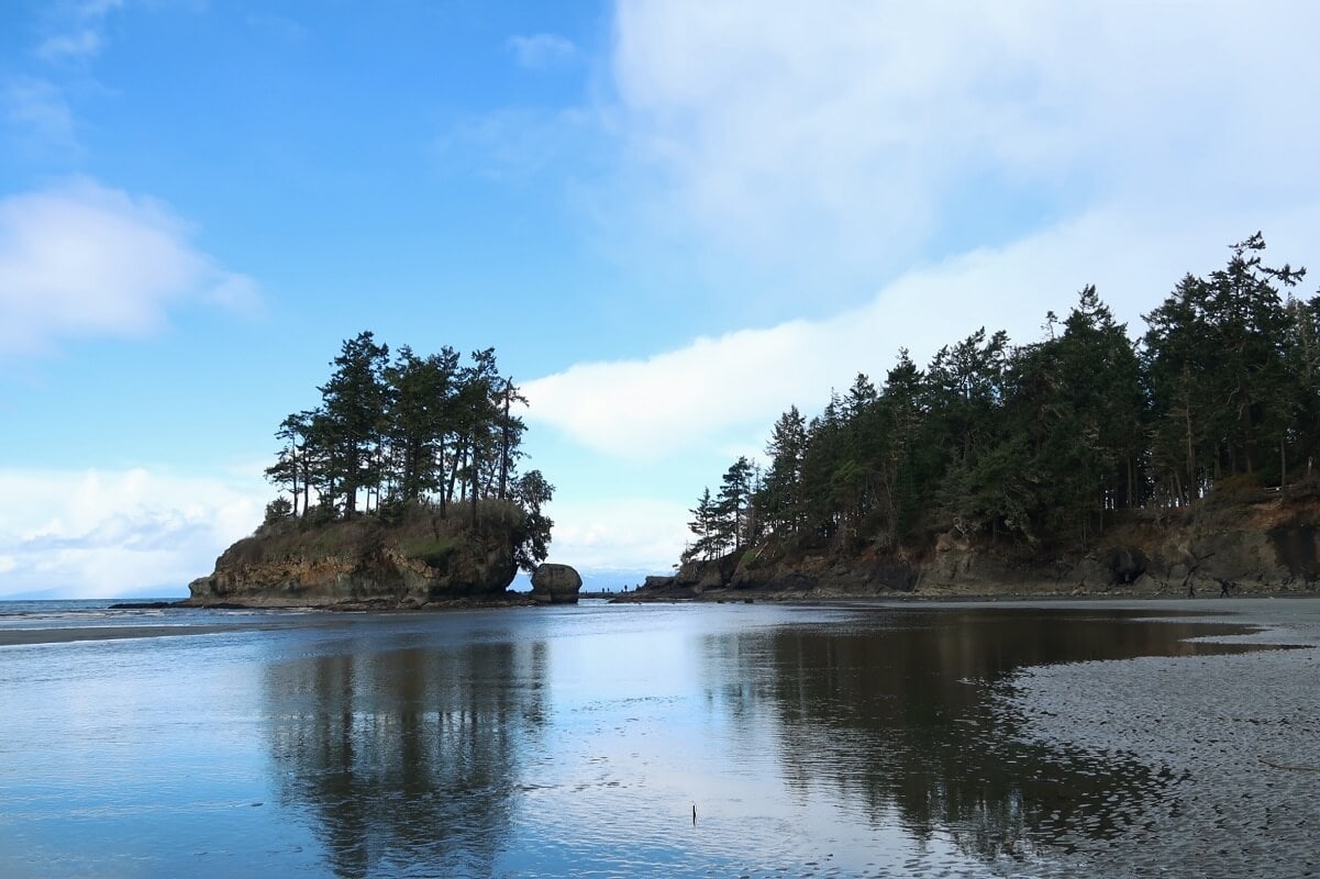 How to spend a day in Port Angeles? Explore the sandy beach and sea stack covered with evergreen trees at Crescent Bay.