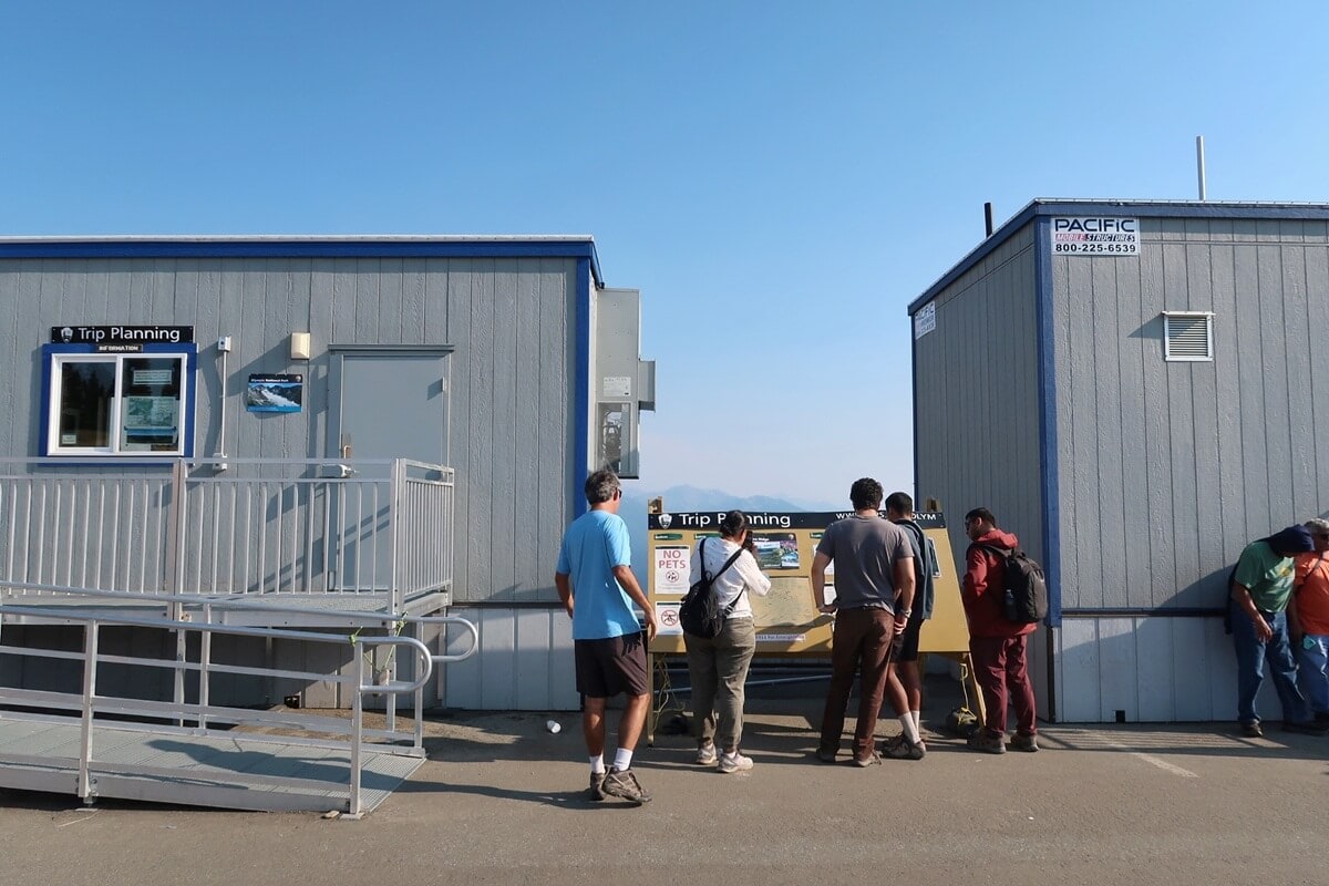 The temporary Hurricane Ridge Visitor Center area features a trip planning station where hikers and tourists gather to check maps and trail conditions. Set between two temporary buildings, the setup provides key visitor information.