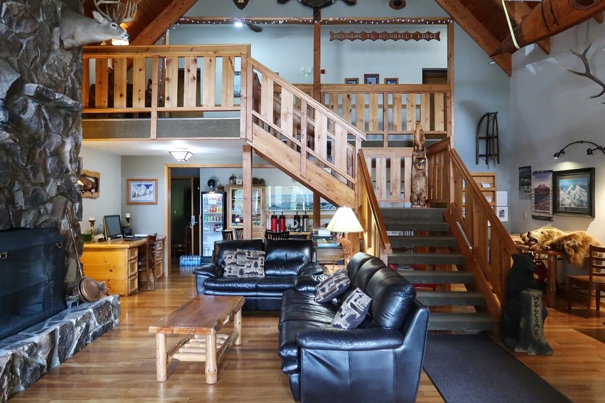 Nisqually Lodge interior, offering an inviting atmosphere for travelers looking for where to stay near Mount Rainier. The space includes a staircase to a loft, log furniture, and mountain-themed decor.