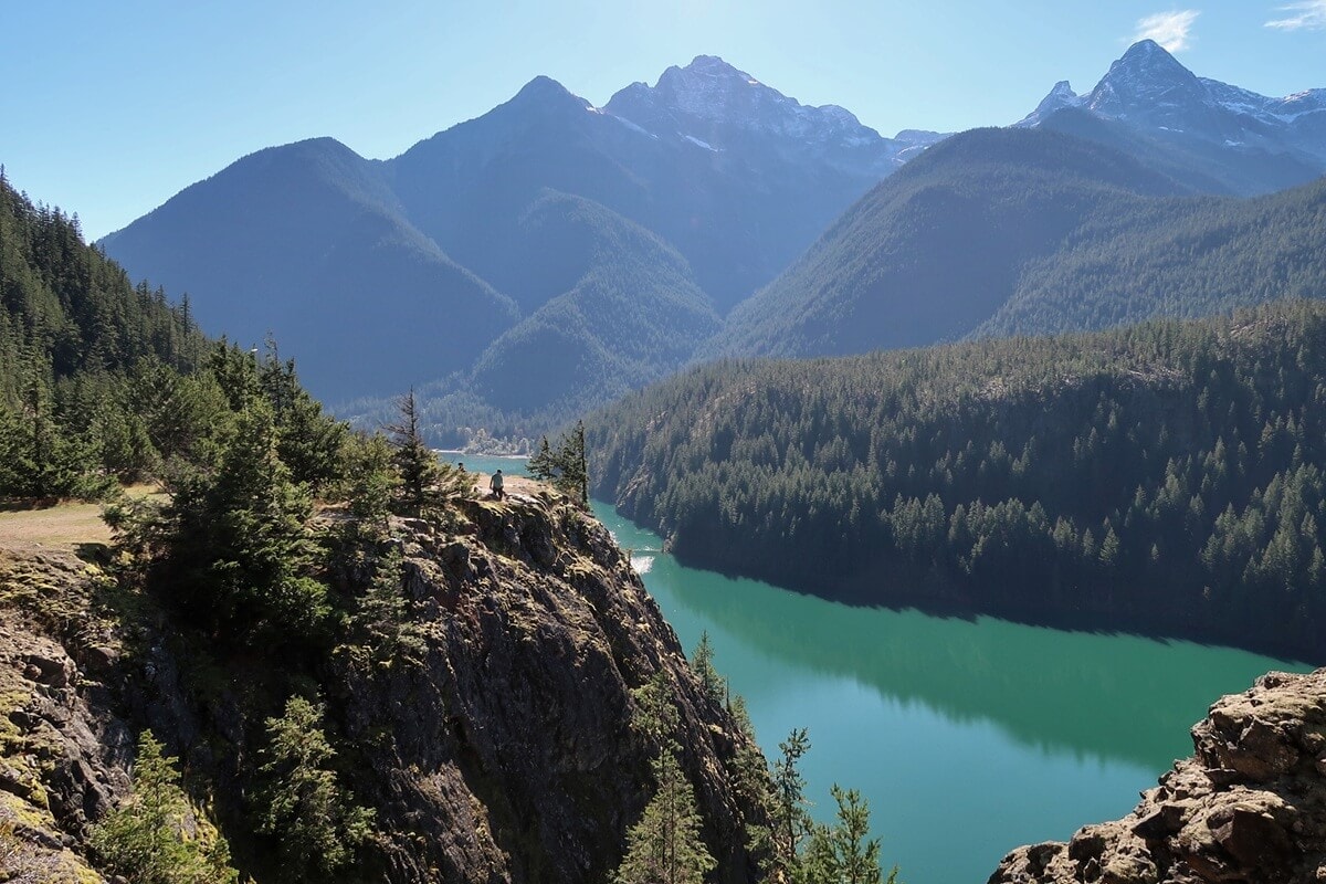 A sweeping view from Diablo Lake Vista Point overlooks the turquoise waters of Diablo Lake winding through a forested valley beneath towering mountain peaks.